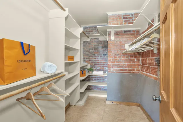a view of a brick house with a large tree and wooden fence