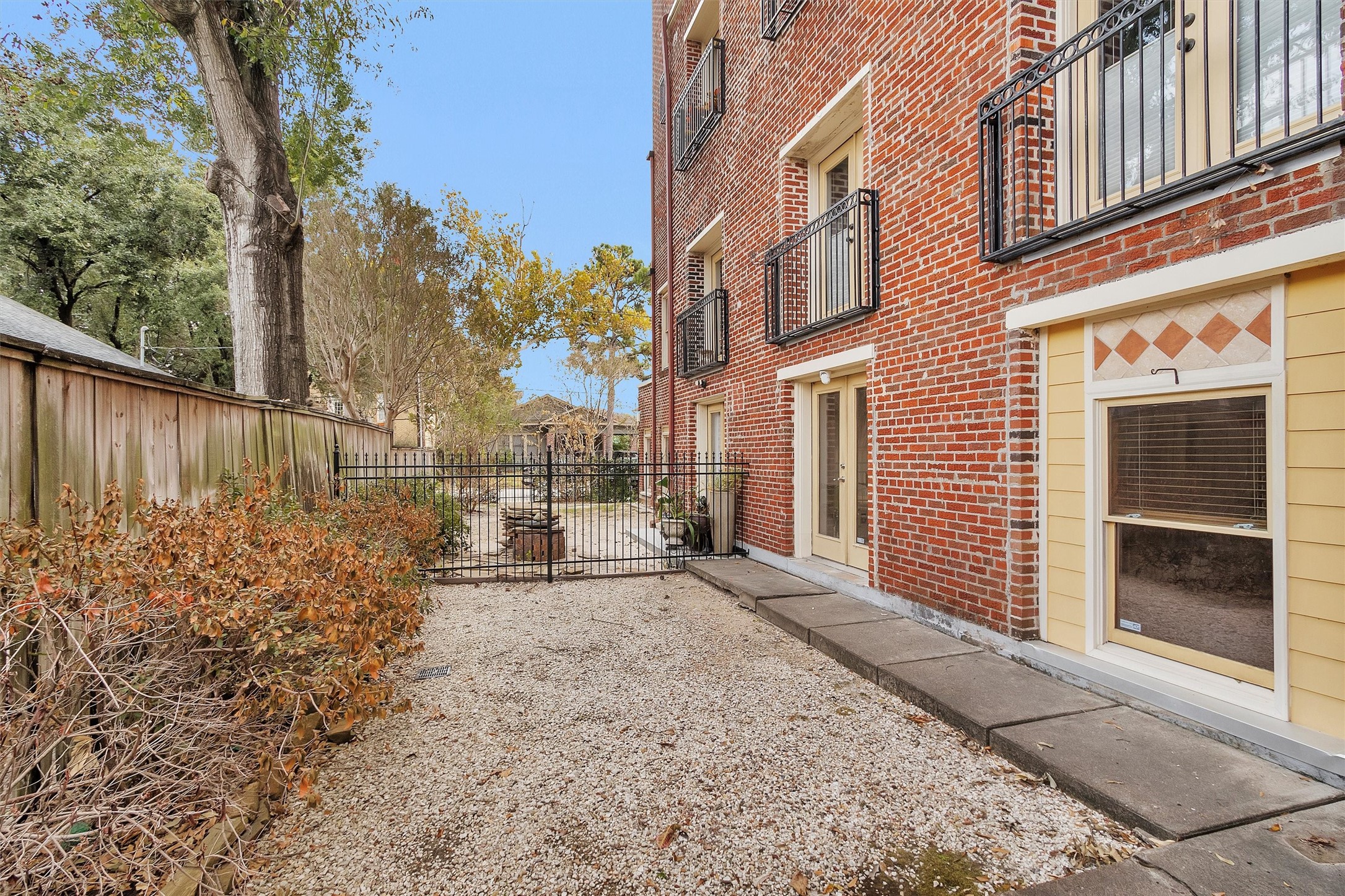 215 West Norma Street, Unit 104 Houston, TX 77009 - Photo 33 of 37 a view of a brick house with a large tree and wooden fence