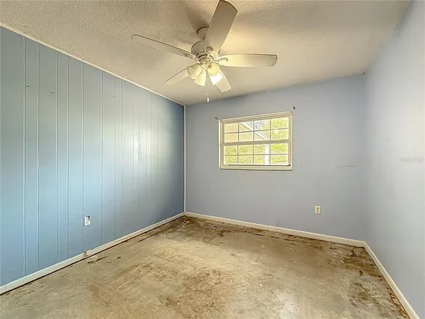 an empty room with a window and a fan