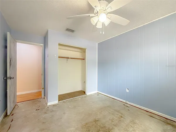 an empty room with a chandelier fan and closet