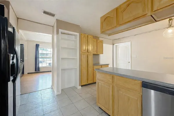 a view of a refrigerator in kitchen and an empty room