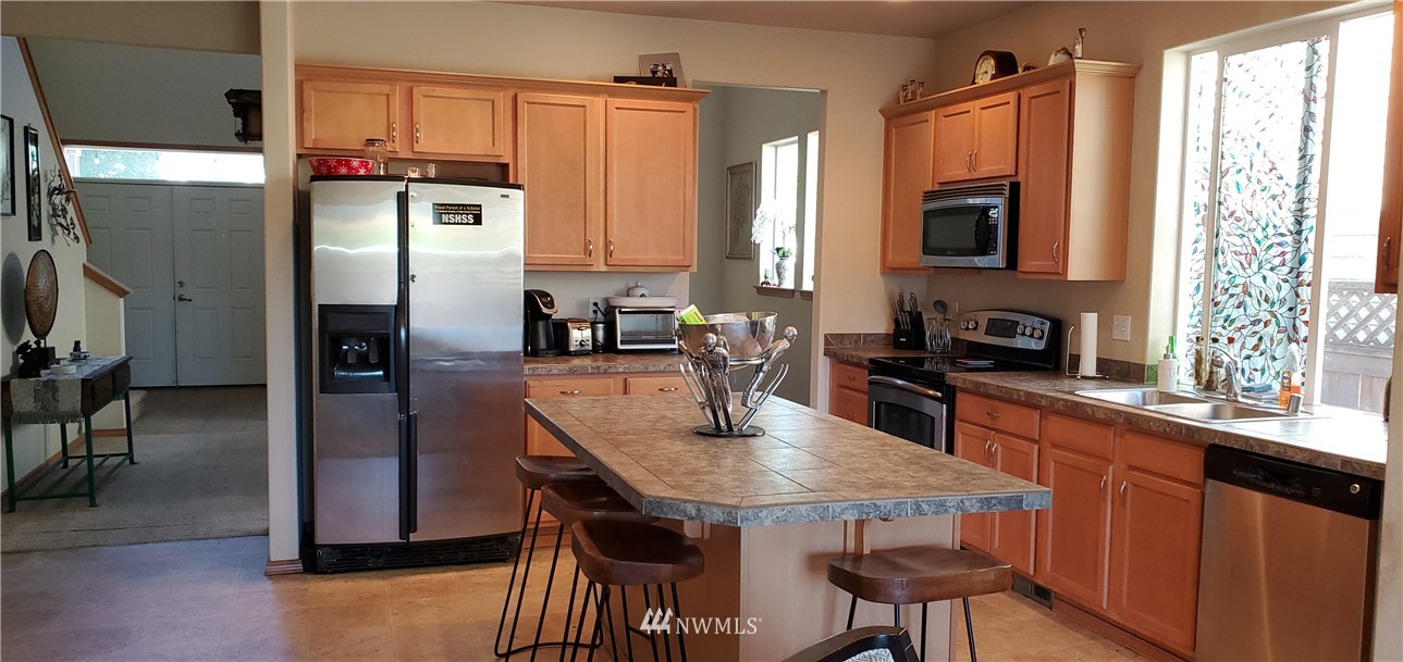 7365 Radius Loop Southeast Lacey, WA 98513 - Photo 12 of 28 a kitchen with stainless steel appliances a sink a stove a refrigerator cabinets and a dining table