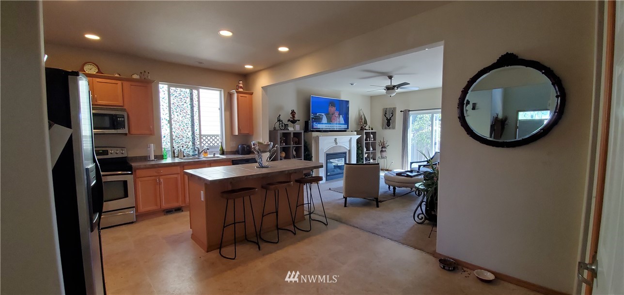 7365 Radius Loop Southeast Lacey, WA 98513 - Photo 6 of 28 a kitchen with kitchen island granite countertop a sink refrigerator stove and a microwave