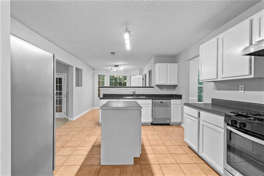 498 Pecan Wood Circle Fairburn, GA 30213 - Photo 7 of 27 a kitchen with stainless steel appliances granite countertop a stove top oven a sink a counter top space and cabinets