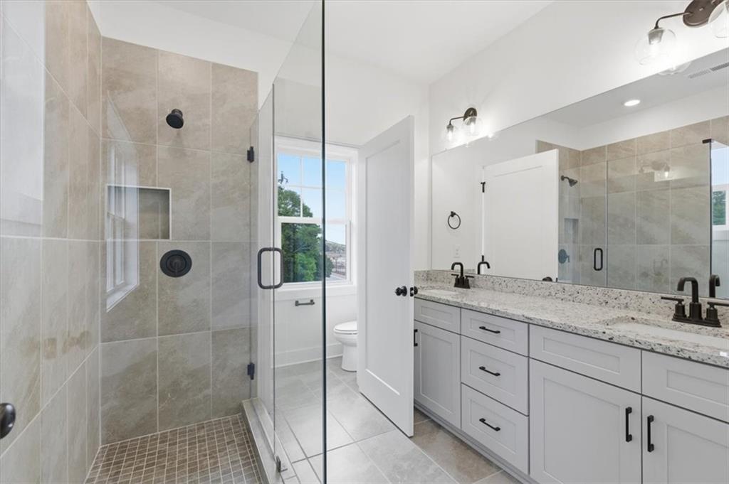 208 Mission Way Atlanta, GA 30315 - Photo 28 of 43 a bathroom with a granite countertop sink a mirror a glass door a shower and vanity