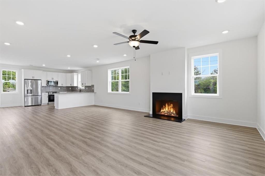 208 Mission Way Atlanta, GA 30315 - Photo 3 of 43 an empty room with wooden floor a ceiling fan a fireplace and windows