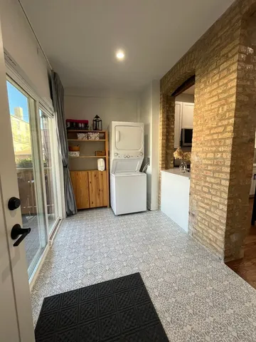 a living room with stainless steel appliances furniture a rug and a kitchen view