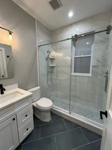 a bathroom with a shower sink mirror and toilet