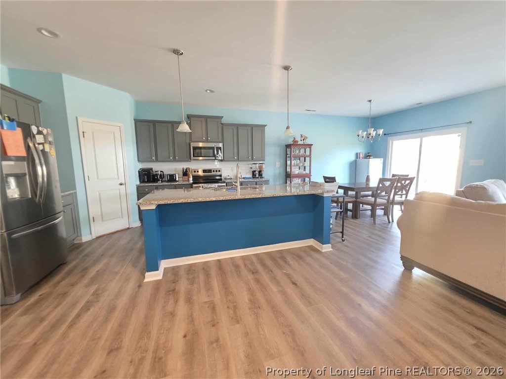 317 Laurel Lake Road Salemburg, NC 28385 - Photo 23 of 29 a kitchen with stainless steel appliances granite countertop a refrigerator a stove oven a sink dishwasher and a dining table with wooden floor