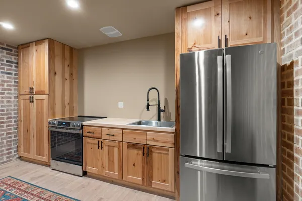 a kitchen with stainless steel appliances granite countertop a refrigerator a sink and white cabinets