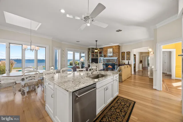 a dining room with stainless steel appliances kitchen island granite countertop a table chairs and a view of living room