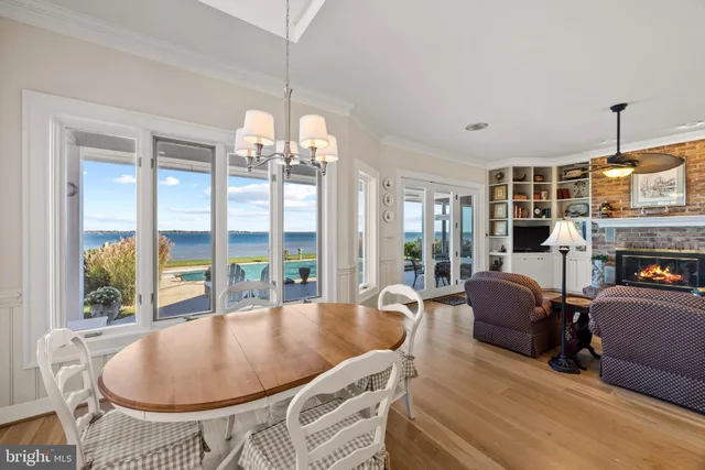 a dining room with wooden floor a chandelier a glass table and chairs