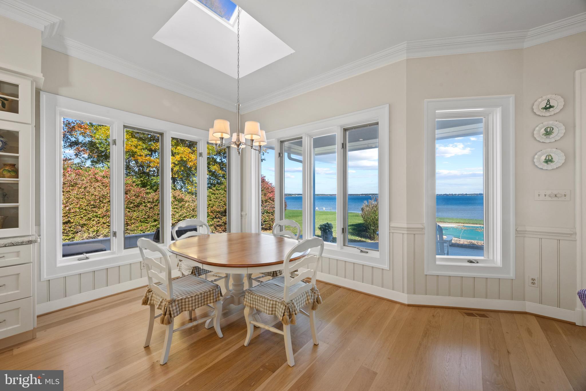 2907 Cox Neck Road East Chester, MD 21619 - Photo 14 of 43 a dining room with wooden floor a chandelier a glass table and chairs