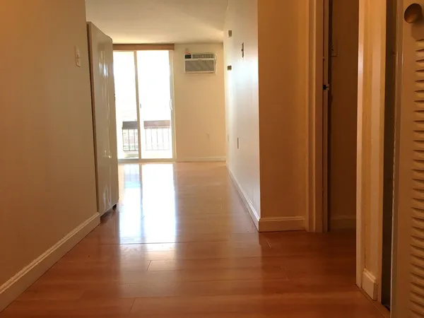 a view of an empty room with wooden floor and a window