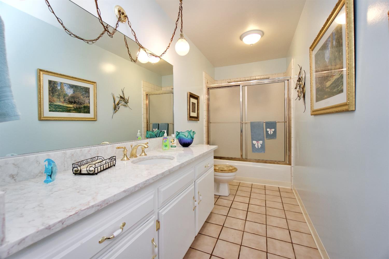 1004 Joy Street Madera, CA 93637 - Photo 19 of 29 a bathroom with a granite countertop sink a mirror a vanity and a shower