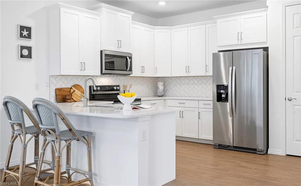 1213 Enbrook Loop Naples, FL 34114 - Photo 7 of 24 a kitchen with stainless steel appliances a refrigerator a sink a stove and white cabinets