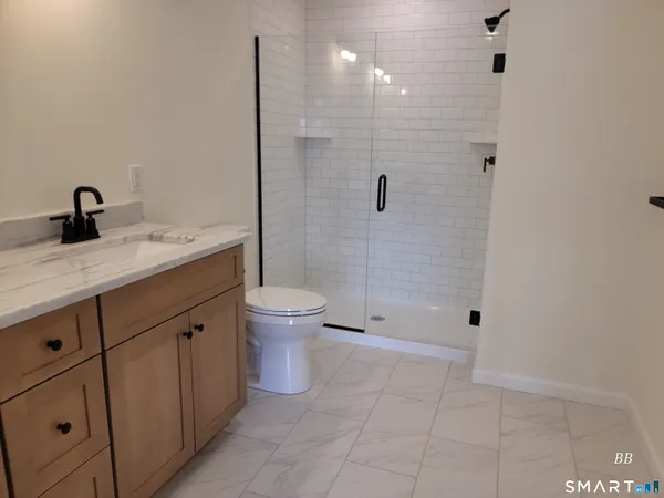 a bathroom with a granite countertop sink a toilet and shower