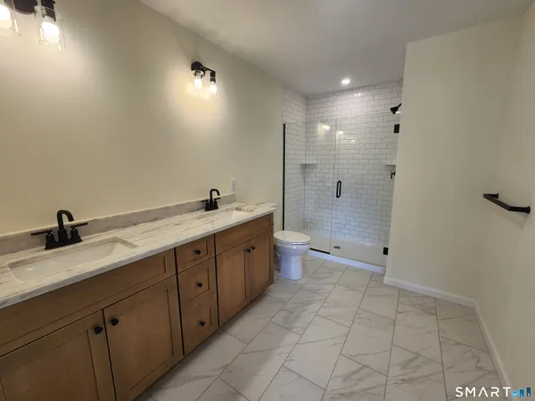 a spacious bathroom with a granite countertop sink a toilet and shower
