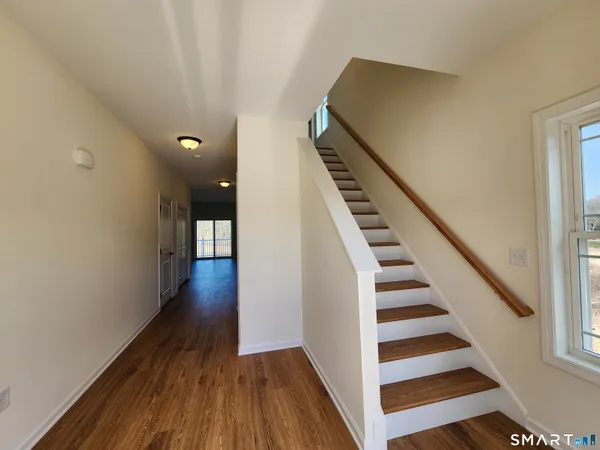 a view of a hallway with wooden floor and staircase