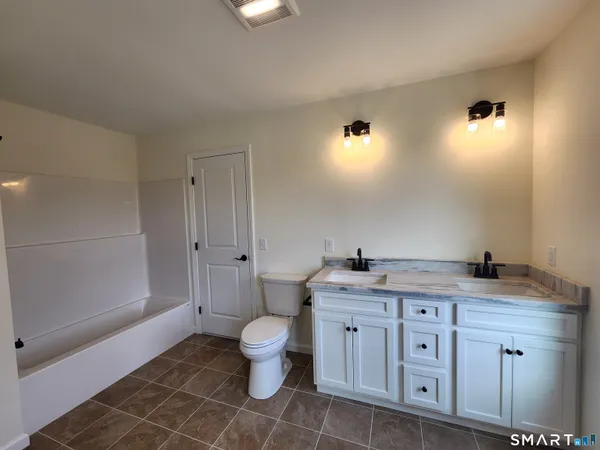 a spacious bathroom with a granite countertop sink a toilet and a shower