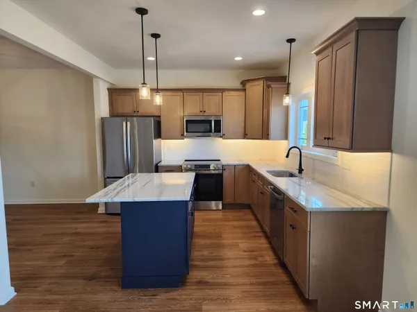 a large kitchen with stainless steel appliances kitchen island granite countertop a sink and a refrigerator