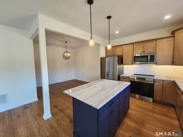 a kitchen with kitchen island a counter top space appliances and wooden floor