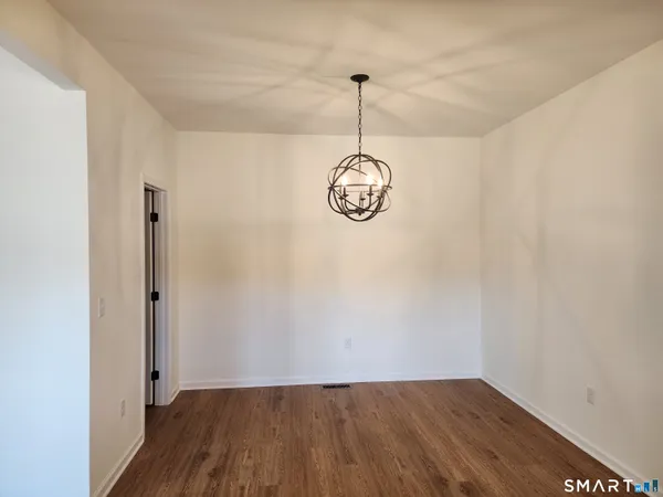 a view of a hallway with wooden floor and a chandelier