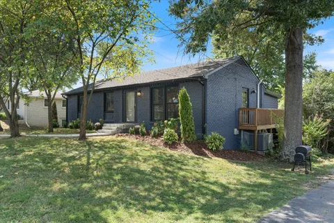 a backyard of a house with table and chairs and potted plants