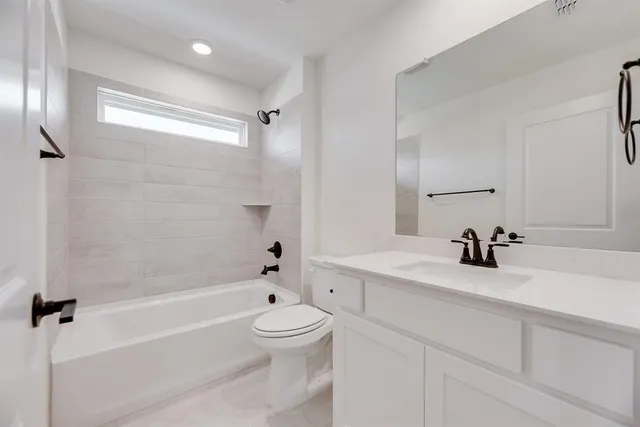 a bathroom with a bathtub shower sink vanity and toilet
