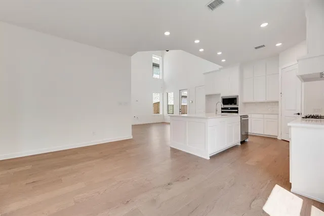 a large white kitchen with kitchen island a sink a stove a oven a dining table and chairs