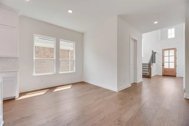 a view of an empty room with window and wooden floor