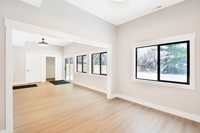 a view of an empty room with a window and wooden floor