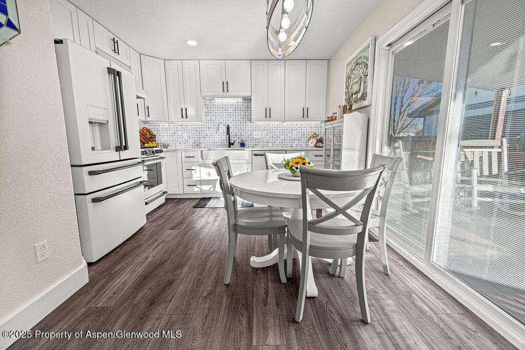 193 Barker Street Craig, CO 81625 - Photo 9 of 50 a kitchen with stainless steel appliances a refrigerator a stove a dining table and chairs with wooden floor