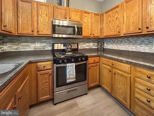 a kitchen with stainless steel appliances granite countertop a stove microwave and cabinets