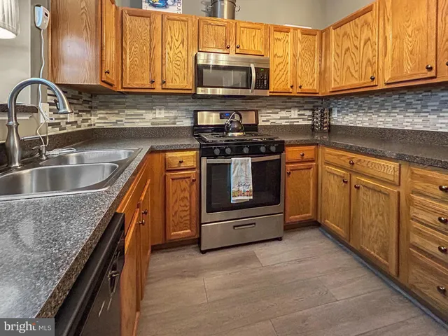 a kitchen with granite countertop a sink stove and microwave