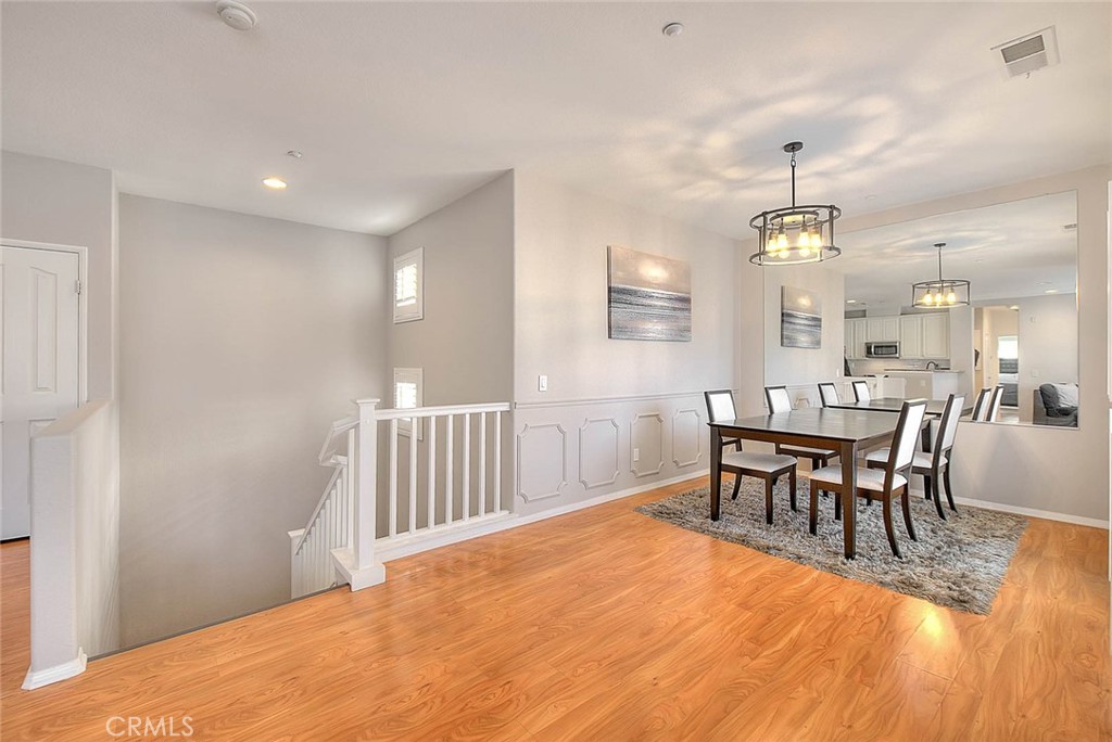 11450 Church Street, Unit 63 Rancho Cucamonga, CA 91730 - Photo 12 of 52 a dining room with wooden floor a chandelier a wooden table and chairs