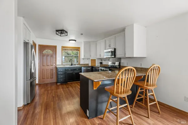 a kitchen with a table chairs a sink dishwasher stove and cabinets with wooden floor