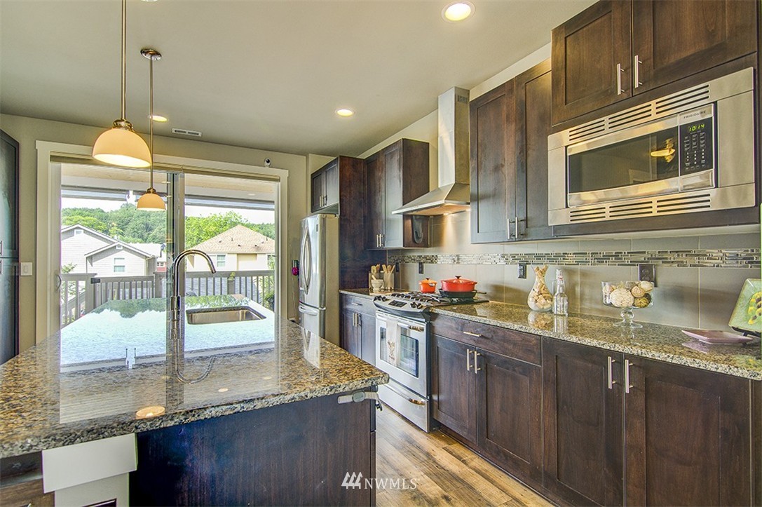 4417 Renton Avenue South Seattle, WA 98108 - Photo 4 of 21 a kitchen with stainless steel appliances granite countertop a sink a stove and a wooden cabinets