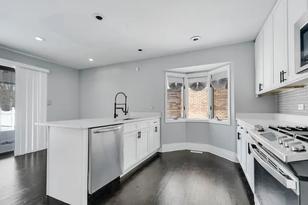 a kitchen with granite countertop a sink cabinets stainless steel appliances and a window