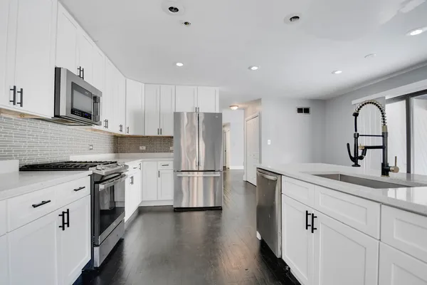 a kitchen with stainless steel appliances granite countertop a refrigerator sink and white cabinets