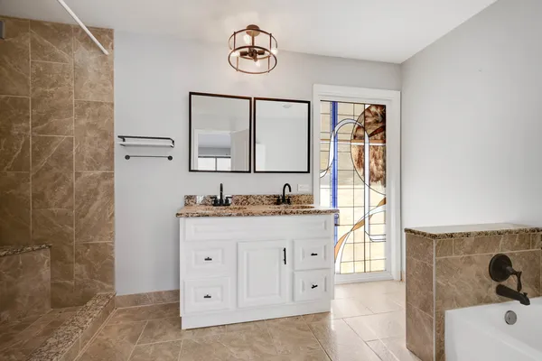 a bathroom with a granite countertop sink a mirror and a bathtub