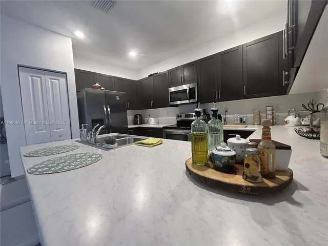 a kitchen with stainless steel appliances granite countertop a sink and a refrigerator