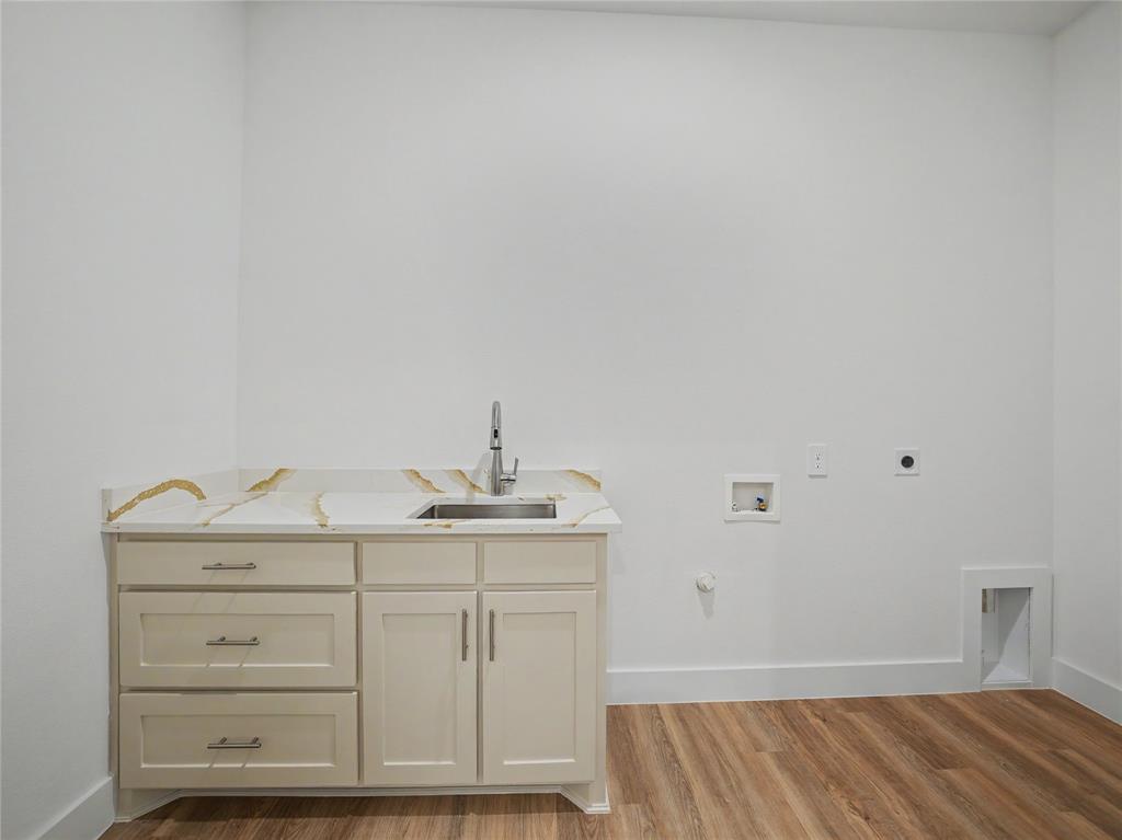 328 Slimp Bluff Azle, TX 76020 - Photo 28 of 30 Laundry room featuring a utility sink with a stainless steel faucet, light-toned cabinetry, and a countertop with gold veining