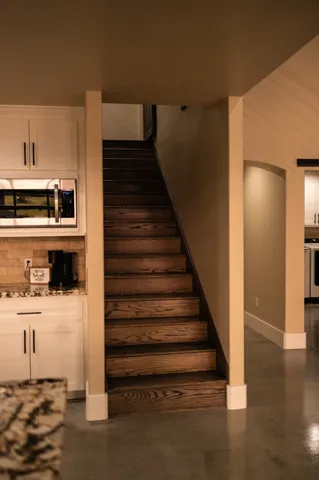 a view of a kitchen with wooden floor electronic appliances and stairs