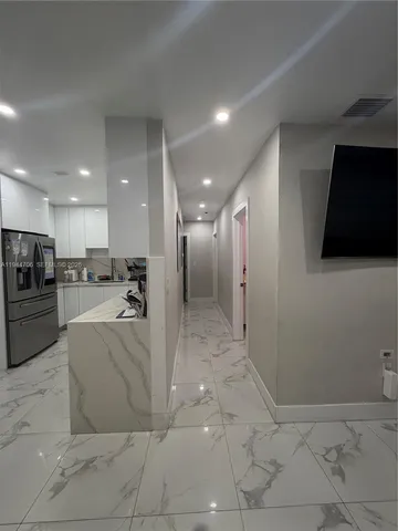 a view of kitchen with stainless steel appliances kitchen island granite countertop a refrigerator a stove a oven and a sink with white cabinets