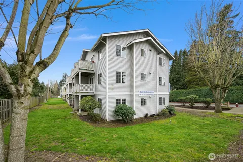 a view of a white house with a big yard and large trees