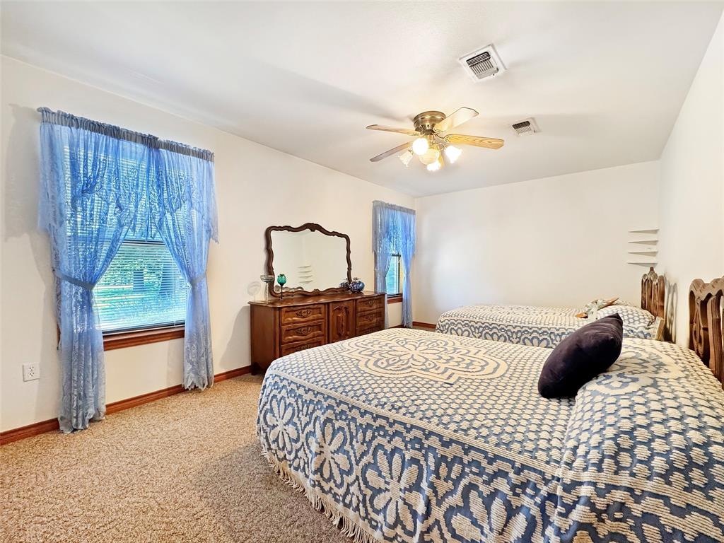 3870 County Road Arthur City, TX 75411 - Photo 17 of 39 Carpeted interior space featuring a window with blue sheer curtains and a wood-finish baseboard