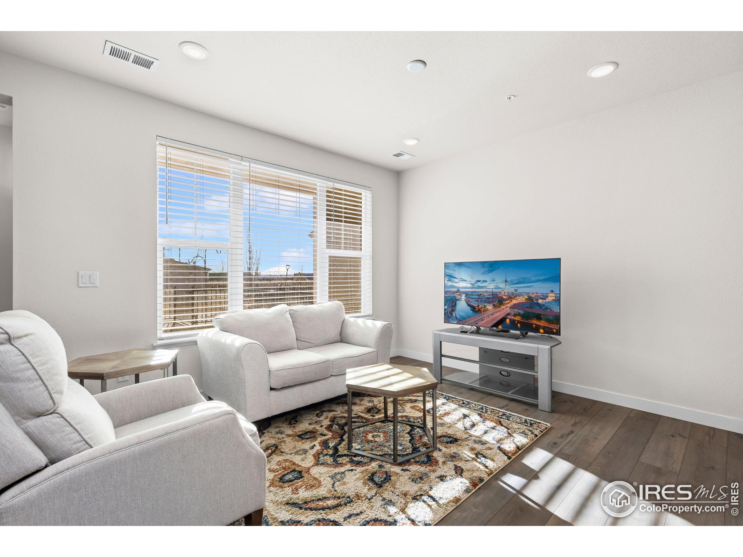 330 High Point Drive, Unit B103 Longmont, CO 80504 - Photo 6 of 18 a living room with furniture a rug and a flat screen tv