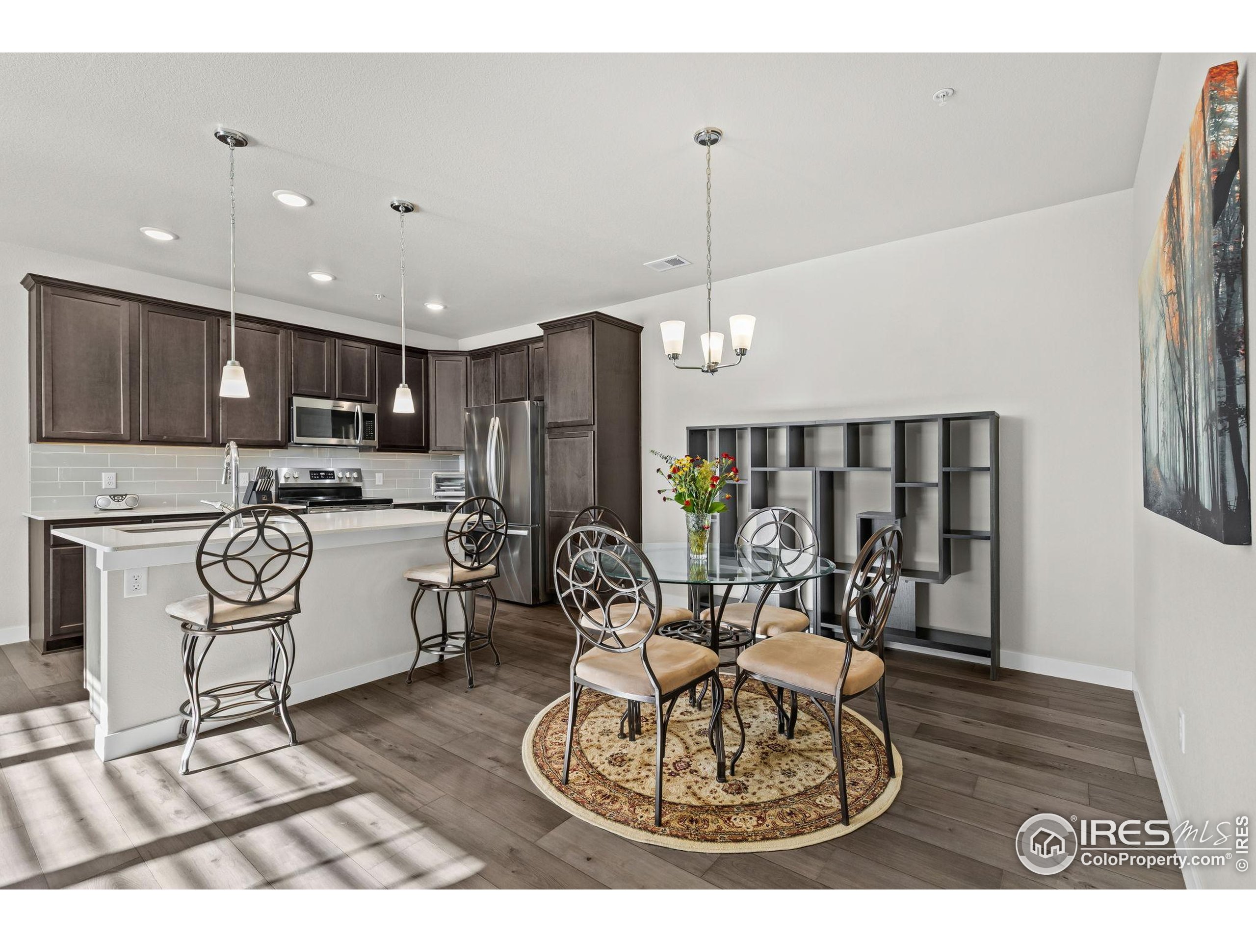 330 High Point Drive, Unit B103 Longmont, CO 80504 - Photo 8 of 18 a open kitchen with stainless steel appliances granite countertop a refrigerator a stove a sink dishwasher a dining table and chairs with wooden floor