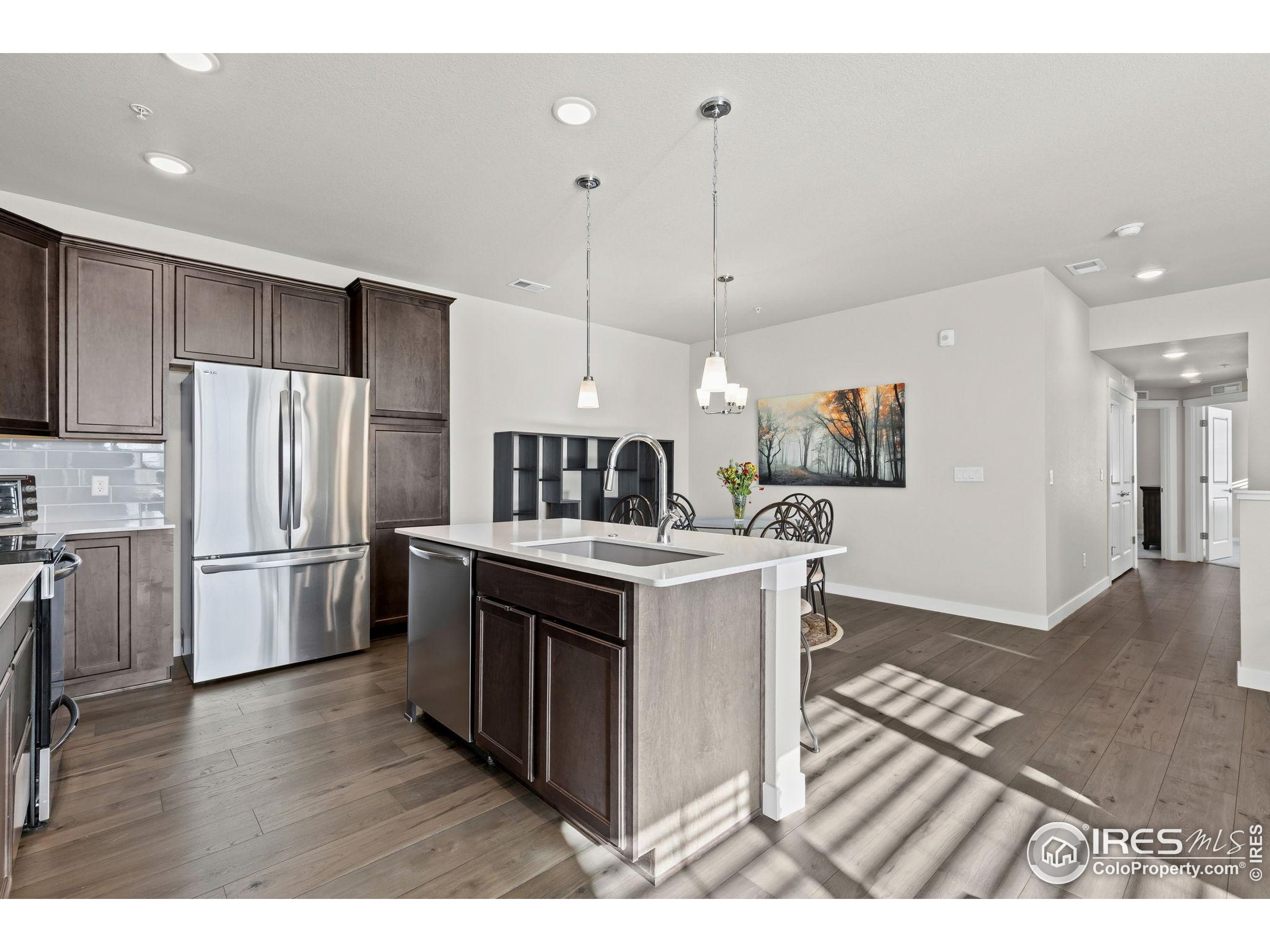330 High Point Drive, Unit B103 Longmont, CO 80504 - Photo 9 of 18 a kitchen with stainless steel appliances kitchen island a refrigerator sink and cabinets